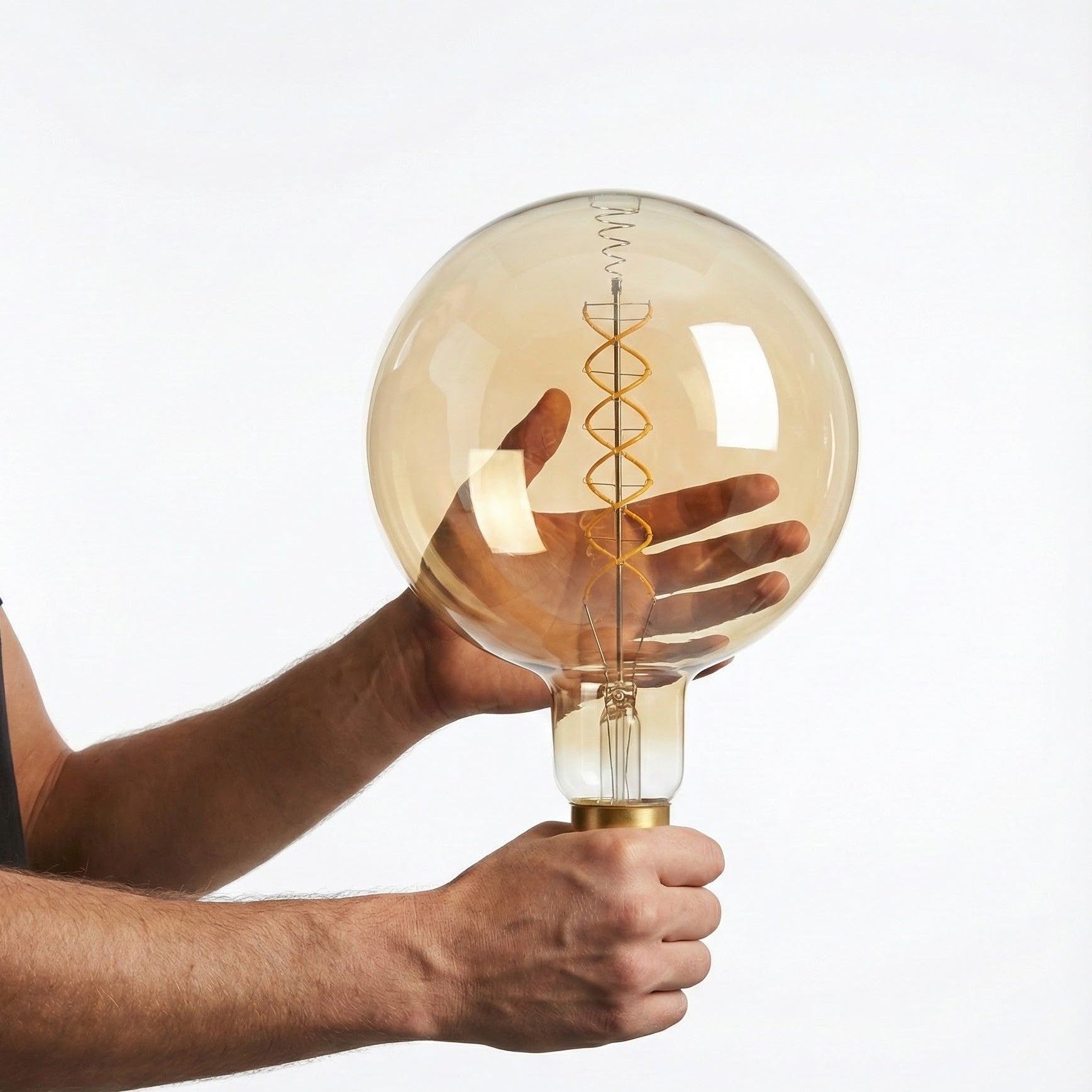 Person holding a large, round, vintage-style light bulb against a plain background