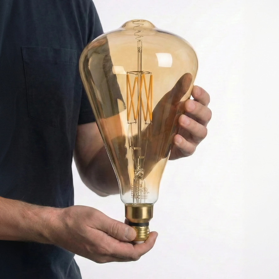 Person holding a large, vintage-style light bulb against a plain background